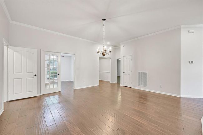 This view from the spacious dining room reveals double French doors that open into a versatile front-facing study—perfect for a home office, playroom, or library—all framed by elegant crown molding and rich engineered wood floors throughout. | Image 7