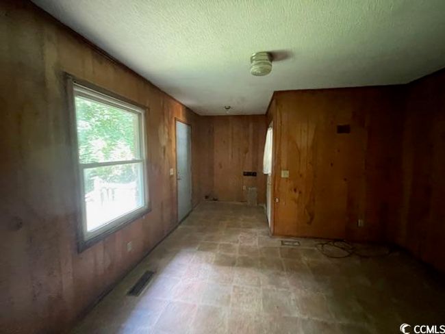 Unfurnished room with wooden walls and a textured ceiling | Image 12
