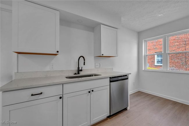 Kitchen with white cabinets, a sink, light wood-type flooring, a textured ceiling, and stainless steel dishwasher | Image 9