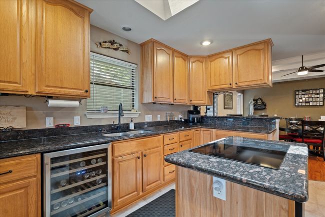 Kitchen featuring wine cooler, a sink, black electric stovetop, a kitchen island, and dark stone countertops | Image 17