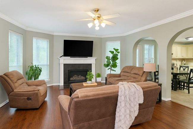 Living area with a ceiling fan, dark wood-style floors, plenty of natural light, and ornamental molding | Image 13