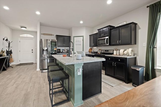 Kitchen featuring appliances with stainless steel finishes, light ceramic tile, a sink, dark cabinets, and an island | Image 12