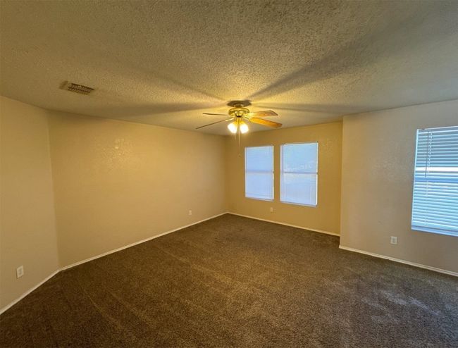 Carpeted spare room featuring a textured ceiling and ceiling fan | Image 11