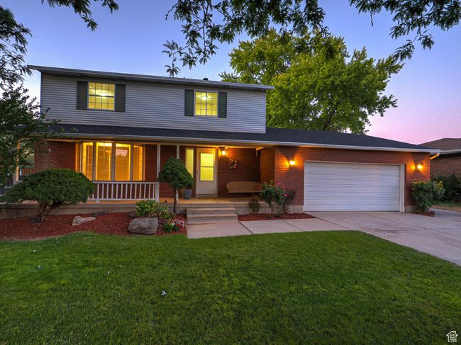Traditional-style house featuring driveway, covered porch, an attached garage, a front yard, and brick siding | Image 6