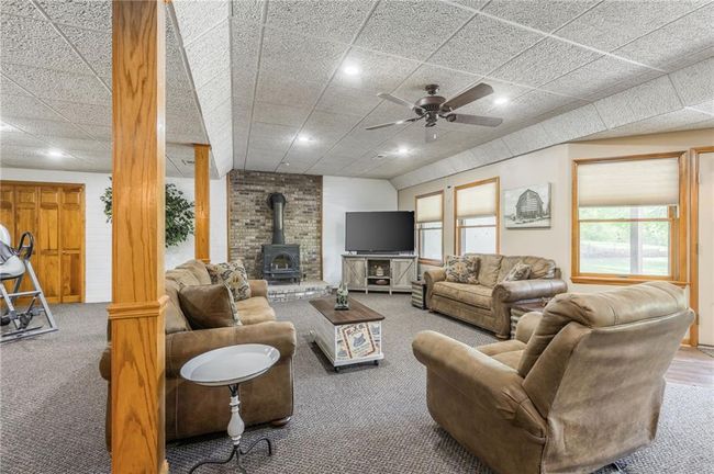 Carpeted living room featuring a wood stove, ceiling fan, and recessed lighting | Image 58