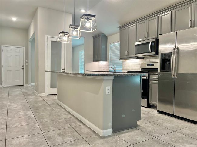 Discover elegance in this gourmet kitchen, featuring a sophisticated sandblasted glass pantry door and stylish lighting. | Image 6