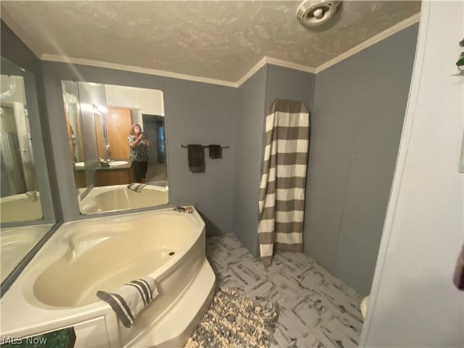 Bathroom featuring a bath to relax in, tile flooring, vanity, and ornamental molding | Image 11