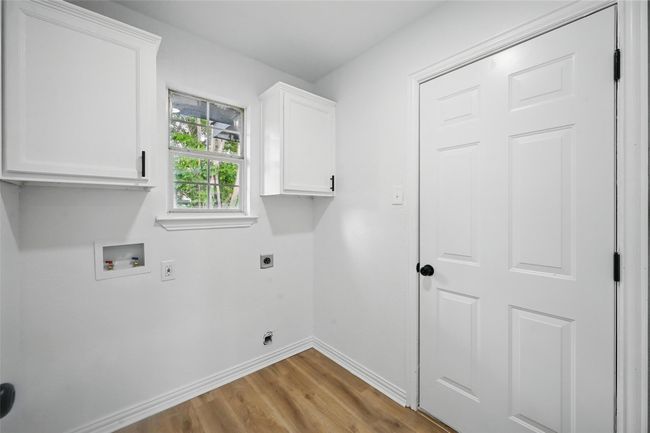 Laundry area with electric dryer hookup, baseboards, cabinet space, light wood finished floors, and hookup for a washing machine | Image 21