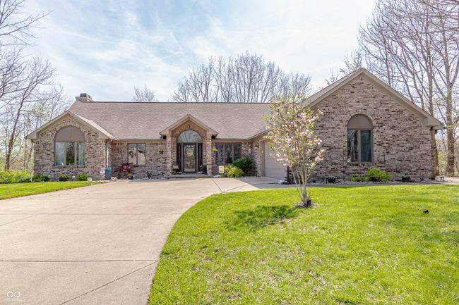 ranch-style home featuring a chimney, roof with shingles, concrete driveway, brick siding, and a garage | Image 48