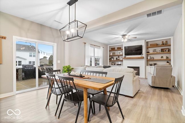 dining space with light wood-style floors, a fireplace, ceiling fan, and a chandelier | Image 17