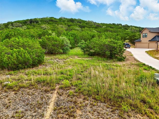 View of yard with a garage, a wooded view, and concrete driveway | Image 11