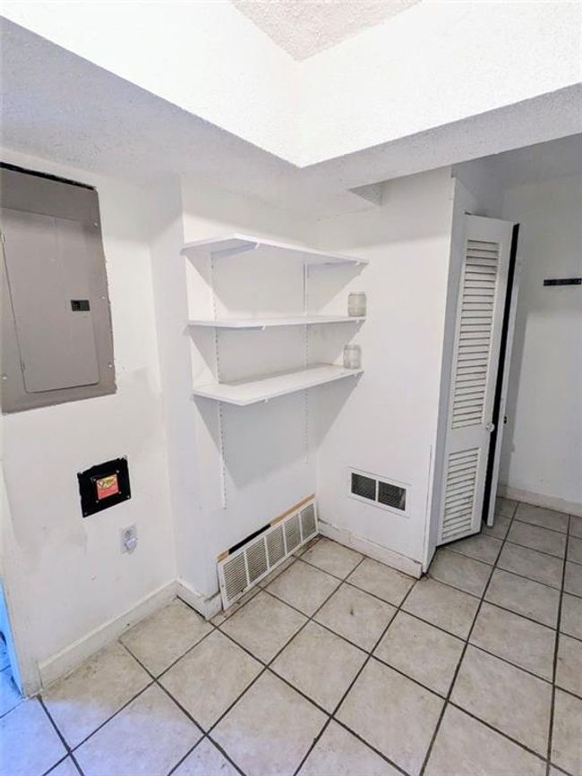 Laundry area with electric panel, light tile patterned floors, and a textured ceiling | Image 14