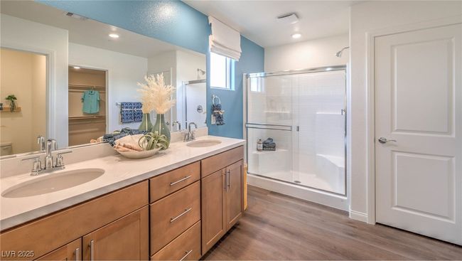 Photo is representational only; actual home finishes may vary. Full bath featuring a shower stall, double vanity, wood finished floors, and recessed lighting | Image 10