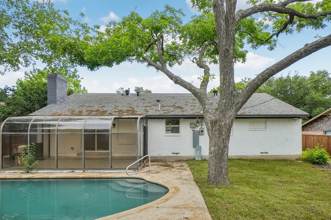 Rear view of property with brick siding, a chimney, an outdoor pool, and roof with shingles | Image 39