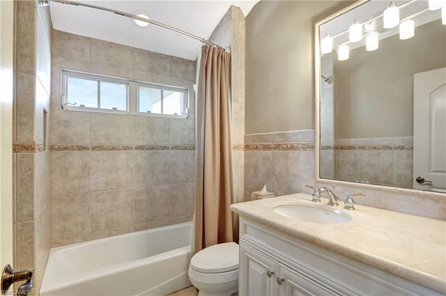 Full bath featuring toilet, shower / bath combo, vanity, and tile walls | Image 9