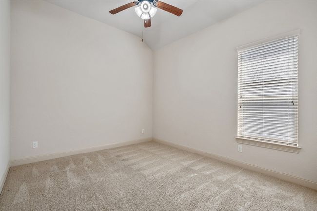 Empty room with light colored carpet, a ceiling fan, and vaulted ceiling | Image 7