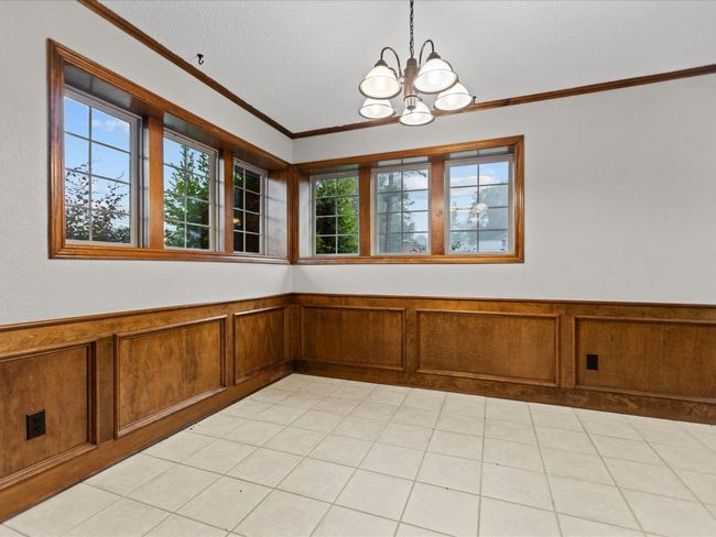 Unfurnished dining area featuring a chandelier, ornamental molding, a wainscoted wall, and a textured ceiling | Image 18
