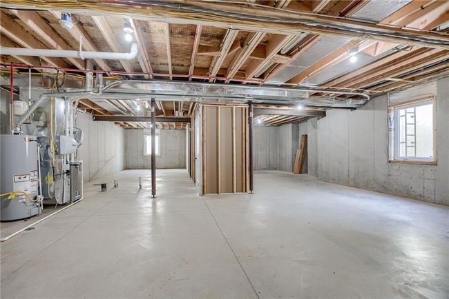 Below grade area featuring gas water heater, plenty of natural light, and heating unit | Image 24