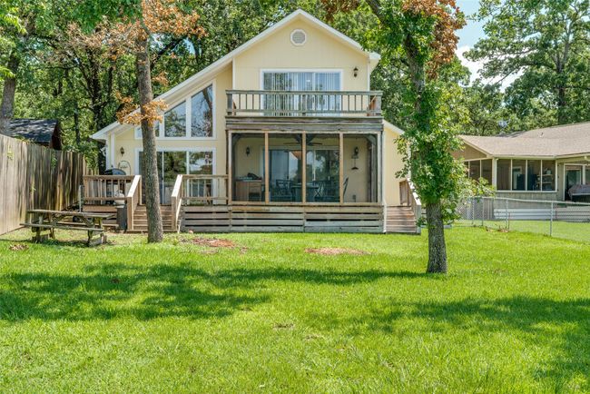 Rear view of house with a sunroom, a balcony, a fenced backyard, and a wooden deck | Image 23