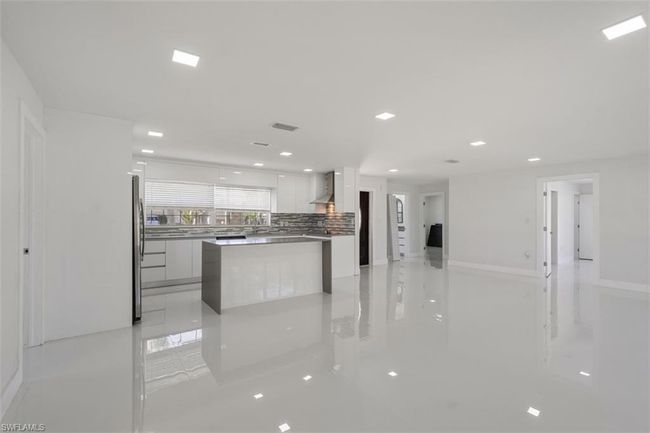 Kitchen featuring freestanding refrigerator, decorative backsplash, white cabinets, wall chimney exhaust hood, and modern cabinets | Image 5
