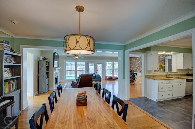 Dining area featuring crown molding, a fireplace, and wood finished floors | Image 14