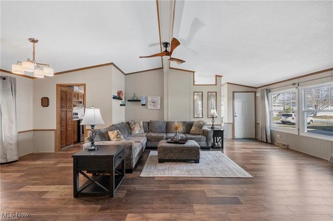 Living area with ceiling fan, ornamental molding, lofted ceiling, and wood finished floors | Image 4