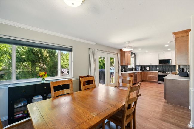 Dining room with ornamental molding, light wood finished floors, recessed lighting, and french doors | Image 5