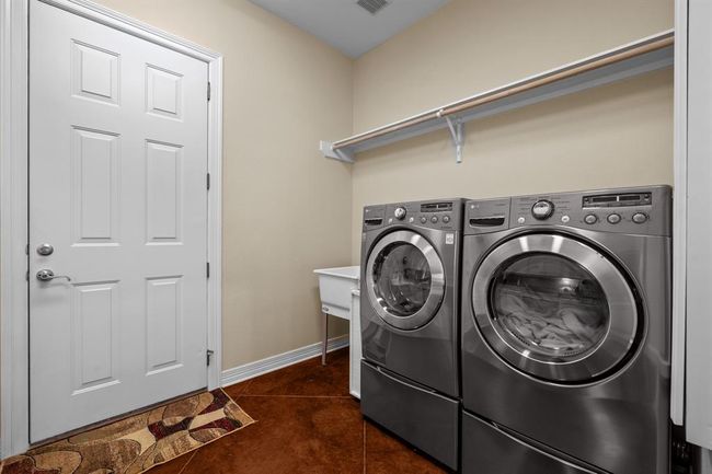 Space for a Front-load washer/dryer set under a hanging rod, with a deep utility sink and direct garage access for ultimate household convenience. | Image 20
