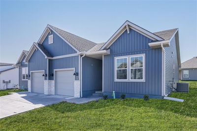 View of front facade with a front lawn, central air condition unit, and a garage | Image 1