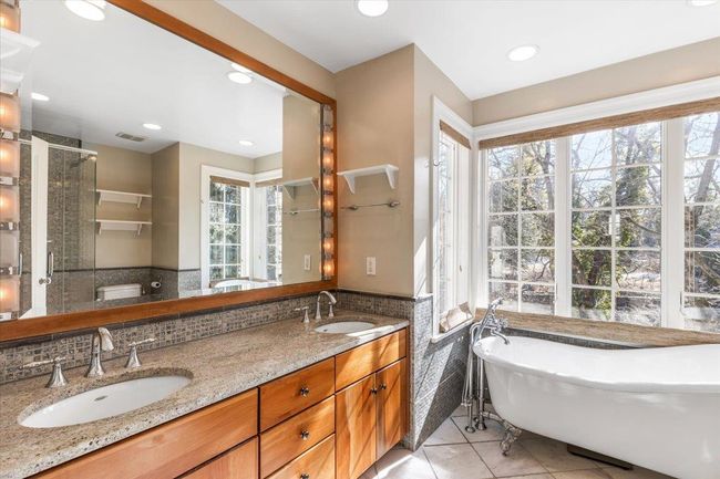 Full bathroom featuring a wainscoted wall, a shower stall, a sink, and tile patterned floors | Image 17