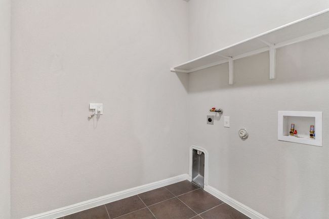 Clothes washing area with hookup for an electric dryer, laundry area, gas dryer hookup, dark tile patterned flooring, and hookup for a washing machine | Image 37