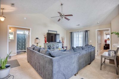 Living room featuring light colored carpet, vaulted ceiling, ceiling fan, and a textured ceiling | Image 2