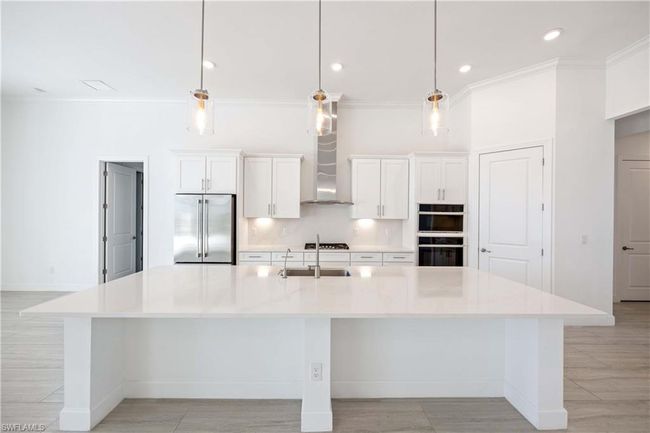 Kitchen with white cabinets, a sink, built in fridge, and a spacious island | Image 9