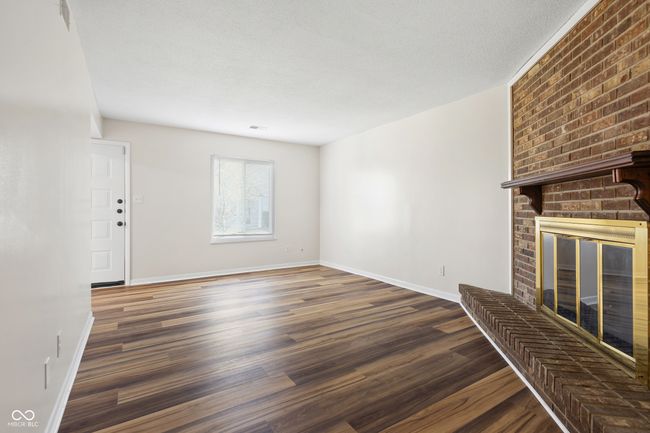 unfurnished living room featuring a fireplace, wood finished floors, and baseboards | Image 6