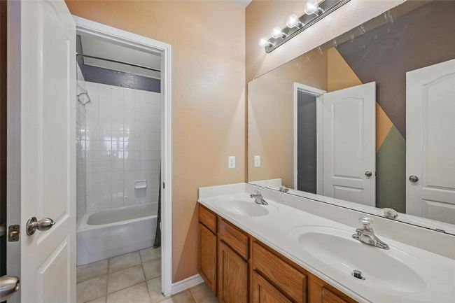 Bathroom with tile patterned floors, double vanity, shower / tub combination, and baseboards | Image 36