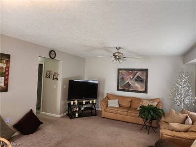 Carpeted living room featuring a textured ceiling and ceiling fan | Image 3