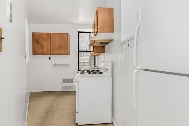 Kitchen featuring white appliances, exhaust hood, brown cabinets, and light flooring | Image 17