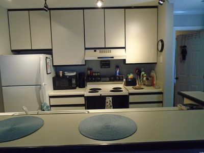 Kitchen featuring white appliances, ventilation hood, and white cabinets | Image 3