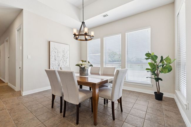 The casual dining space is just off the kitchen and has quick access to the backyard. Enjoy serene views of the pool and backyard. The room boasts tile flooring, tray ceiling and is freshly painted. | Image 10