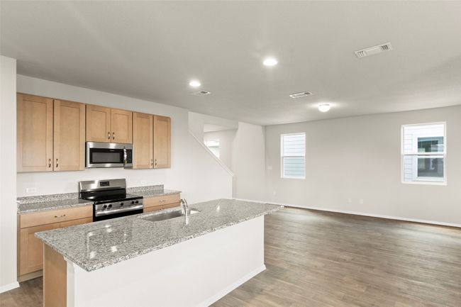 Kitchen featuring appliances with stainless steel finishes, light wood finished floors, an island with sink, light stone counters, and recessed lighting | Image 18