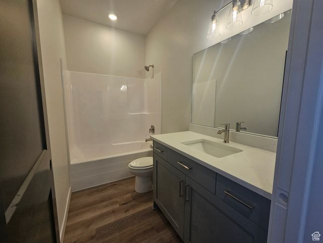 Bathroom featuring wood finished floors, vanity, toilet, shower combination, and recessed lighting | Image 23