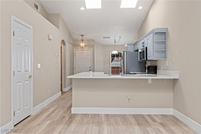 Kitchen featuring arched walkways, a peninsula, light wood finished floors, a breakfast bar area, and light stone counters | Image 17