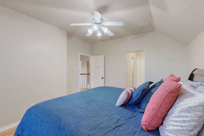 Bedroom with wood finished floors, vaulted ceiling, visible vents, and ceiling fan | Image 29