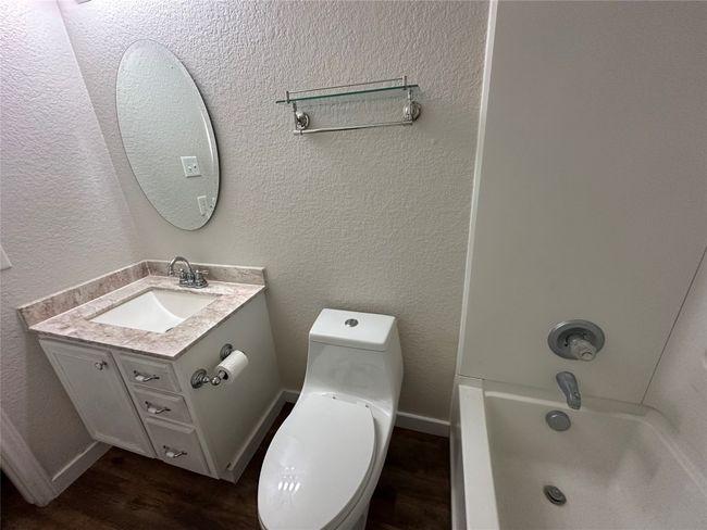 Full bathroom featuring wood finished floors, vanity, a textured wall, and shower / washtub combination | Image 26