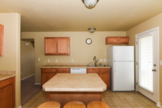 Kitchen featuring a sink, a healthy amount of sunlight, brown cabinetry, and white appliances | Image 13