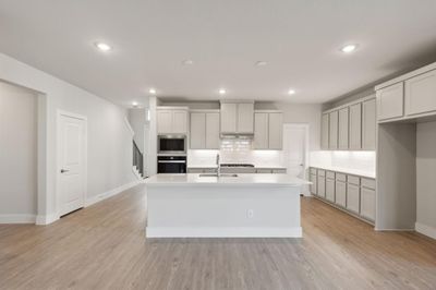 Kitchen featuring stainless steel appliances, light hardwood / wood-style floors, and a center island with sink | Image 2