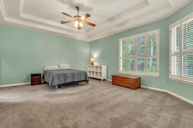 Bedroom with ceiling fan, carpet, a raised ceiling, and crown molding | Image 9