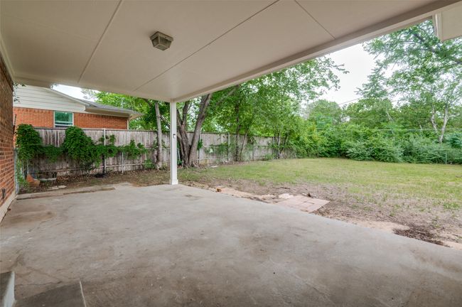View of covered back patio and large backyard. | Image 23