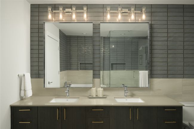 Bathroom featuring double vanity, a shower stall, and tile walls | Image 11