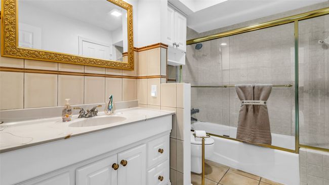 Full bath featuring bath / shower combo with glass door, vanity, and tile patterned flooring | Image 6